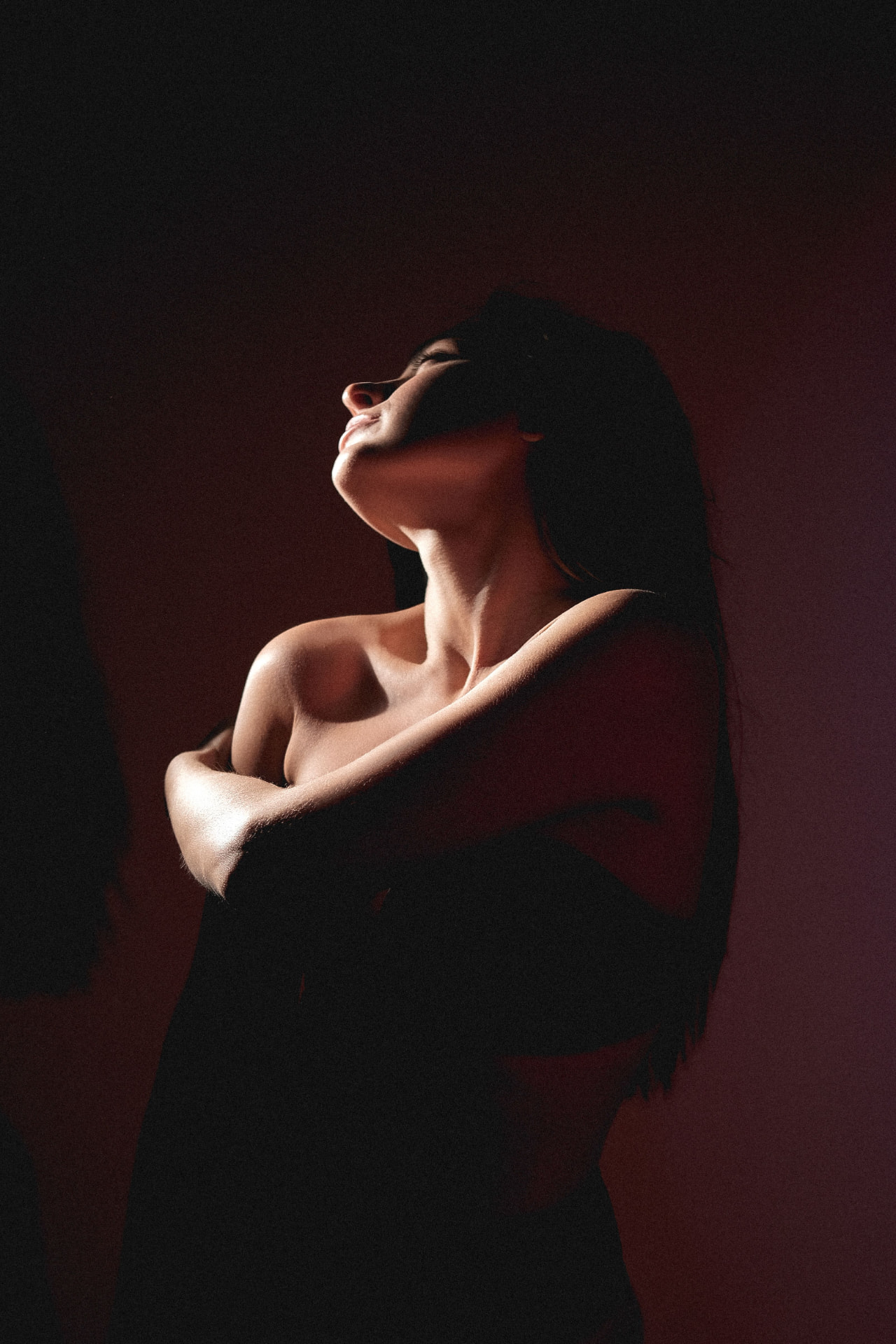 A pregnant woman standing quietly in warm window light, hands resting on her belly